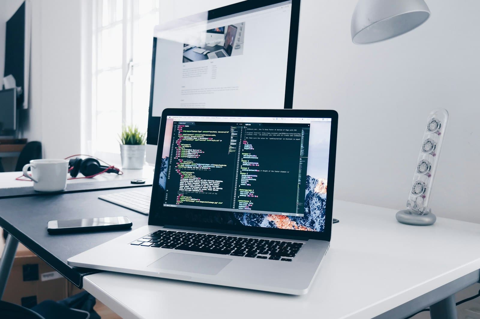 MacBook showing web development code beside agreement notes for a Cochrane web design project